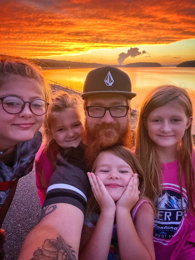 Jason Lowe with his four daughters beside the water at sunset